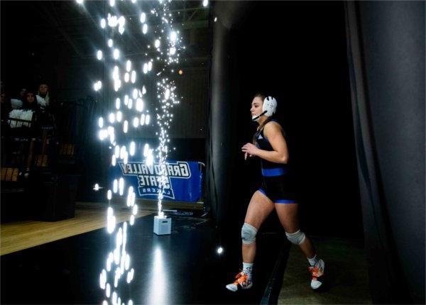    A member of the Women's Wrestling team runs past festive sparks while entering the arena.