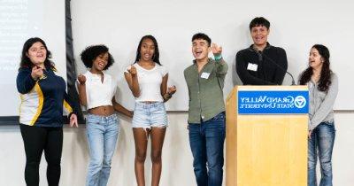 High school students stand behind a podium gesturing while giving a presentation.