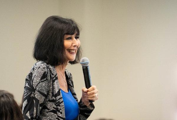 A person holds a microphone while speaking.