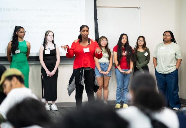 People stand in front of a crowd in a classroom during a presentation.