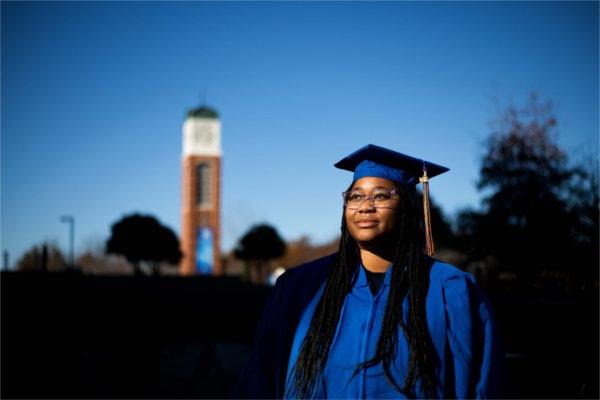 A person wearing blue academic garb looks off to the side. The carillon is in the background.