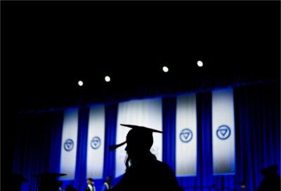 A silhouetted graduate walks in front of the stage during Commencement ceremonies.