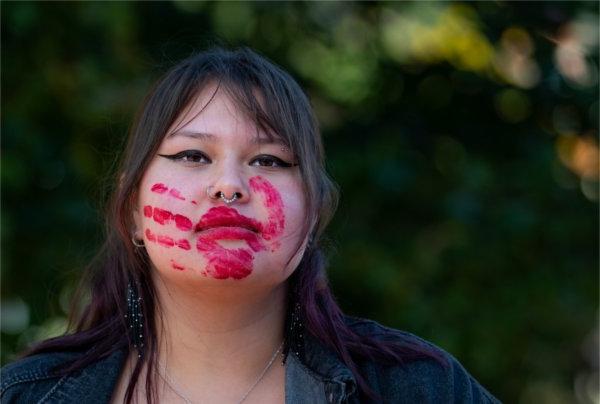  A red hand print is shown on the face and over the mouth of a college student.