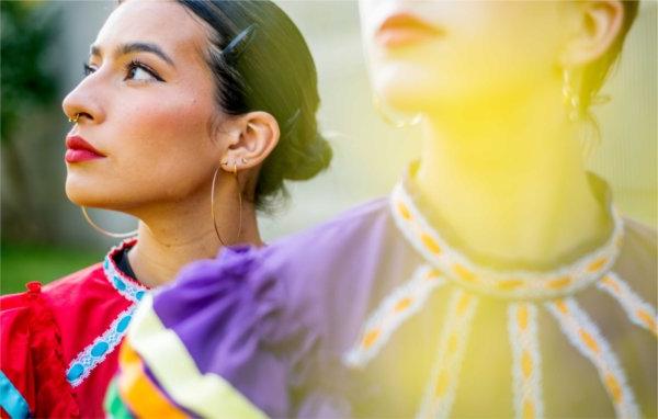 Two folkloric dancers pose for a photo in their colorful traditional dresses.