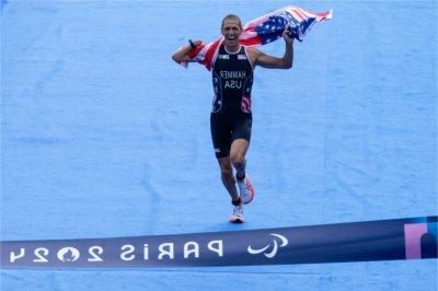 Chris Hammer carries the U.S. flag as he crosses the finish line for his Para Triathlon event at the 2024 Paris Paralympic Games.